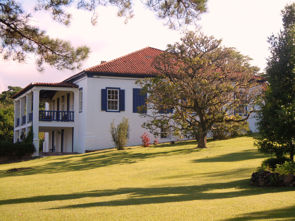 Sede histórica da Fazenda Santa Maria, construída em 1876, com paredes brancas e janelas azuis